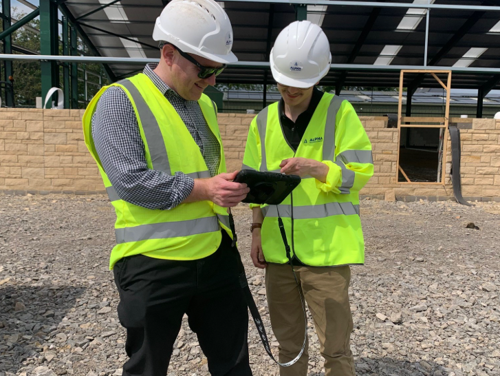 two people in high visual jacket looking at a tablet screen